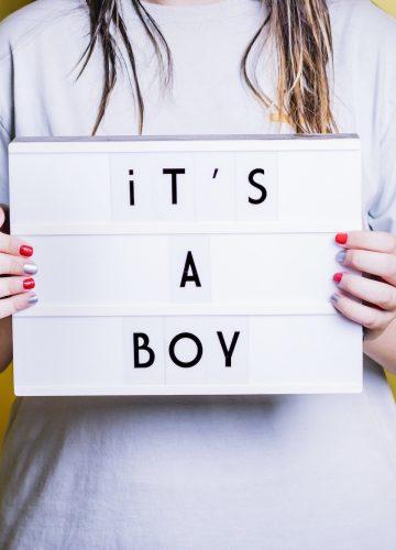 Girl holding a light box with the phrase "it's a boy".