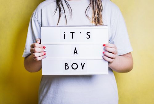 Girl holding a light box with the phrase "it's a boy".