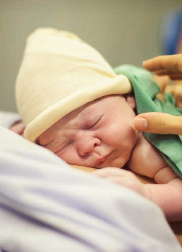 Infant sleeping on faceless mother